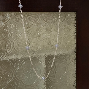 Detail of silver long chain necklace featuring five light blue clover charms on vintage glass