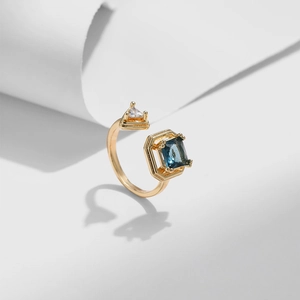 Macro shot of 18K gold plated open ring with blue rectangle and clear triangle stones