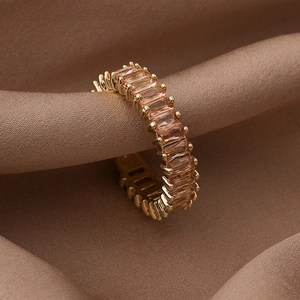 Detail of gold band ring featuring orange rectangular cubic zirconia on brown silk