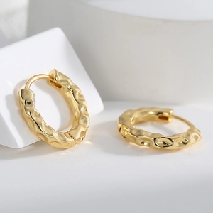 Minimalist gold plated brass hoop earrings with irregular hammered texture on white background