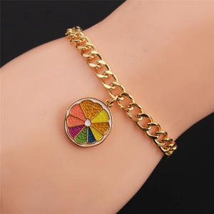Detail of gold chain bracelet with a colorful rainbow orange slice charm on model