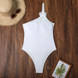 Macro view of white ribbed one-shoulder swimsuit with elegant 3D floral decoration