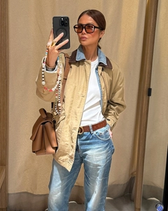 Detail of a khaki patchwork collar jacket styled with blue jeans and a brown leather tote bag