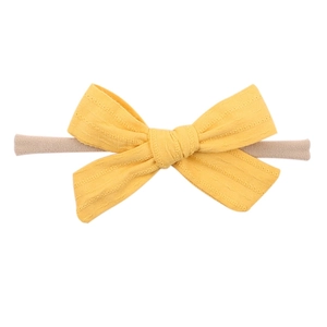Dettaglio della fascia con fiocco giallo testurizzato su elastico in nylon beige