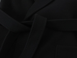 Detailed macro shot of black wool coat waist belt and neat stitching texture
