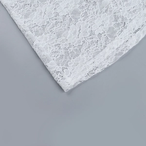 Primo piano dettagliato che mostra l'intricata trama del pizzo floreale e il motivo traforato bianco