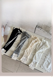 Detailed view of four colors of ballet-style leg warmers with delicate white ribbon bows