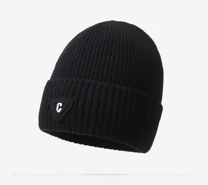 Close-up of a black knit beanie featuring a thick ribbed cuff and a triangle logo patch