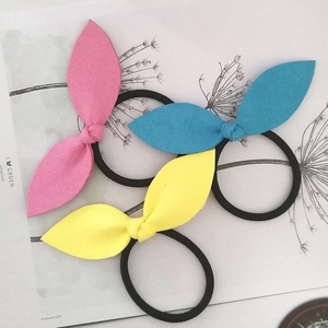 Close-up of rabbit ear hair scrunchies in pink blue and yellow on magazine background