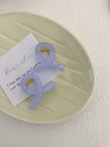 Close-up of lavender purple mini hair claws with gold metal springs on a ceramic plate