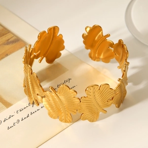 Makroaufnahme der 18K vergoldeten Edelstahl-Armspange mit Blattmotiv auf eleganter Karte