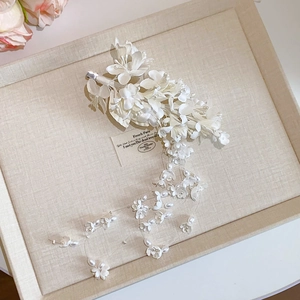 Close-up of handmade white acrylic flower hair clip with pearl tassels and fringe