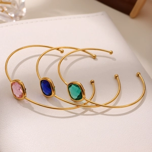Three-piece set of gold-plated open bangles with pink, blue, and green rectangular crystals