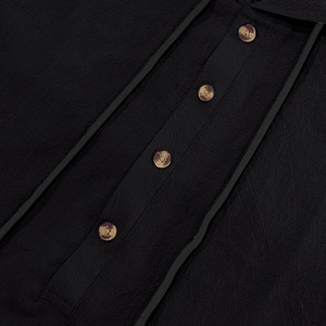 Close-up of black linen shirt fabric with amber buttons and decorative trim details