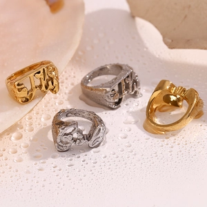 Artistic close-up of 18K gold and silver heart rings on a wet white surface with shells