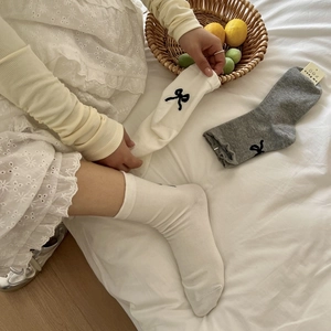 Detailed close-up of Japanese style socks featuring black bows and lace in white and grey