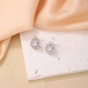 Elegant silver halo square zircon stud earrings with bow accent on white stone background