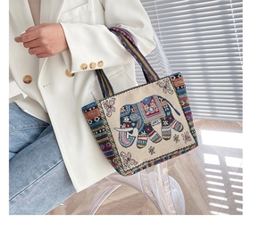 Dettaglio del ricamo colorato di un elefante su borsa in tela beige con manici intrecciati