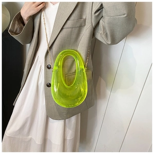 Detail view of neon yellow acrylic U-shaped evening clutch bag with golden chain strap
