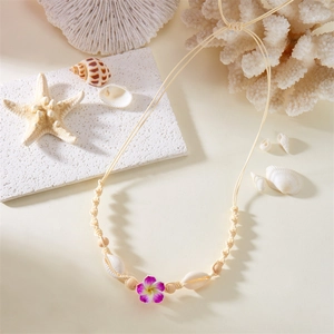Macro view of handmade woven rope necklace with shells and a purple plumeria flower