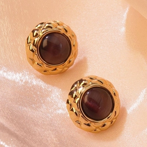 Macro shot of vintage gold quilted texture earrings with purple cat eye stone detail