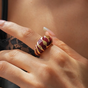 Macro shot of wide gold-plated ring with deep red enamel and spiral texture on hand