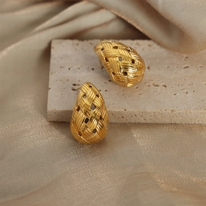 Gold-plated teardrop earrings with woven texture on elegant silk and stone background