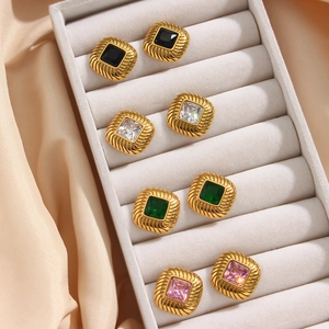 Detail of square zircon earrings in gold setting displayed on grey velvet tray