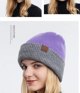 Detail of a purple and grey knit beanie with leather logo patch on a white background