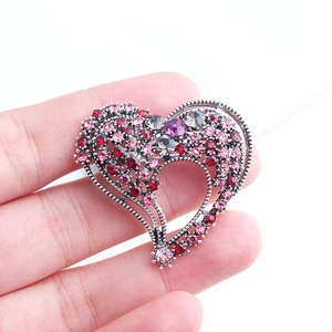 Detailed close-up of heart-shaped brooch with colorful rhinestones in hand