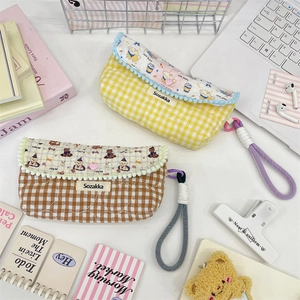 Detailed view of quilted checkerboard pen bags with cute cartoon bear prints and pompoms