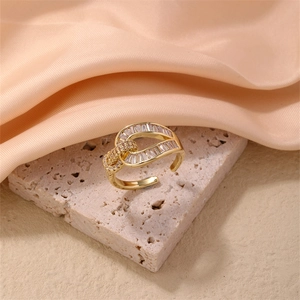 Macro shot of gold adjustable ring featuring baguette cut zircons on a textured stone