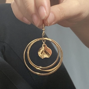 Gros plan de boucles d'oreilles créoles en acier doré 18 carats portées par un mannequin