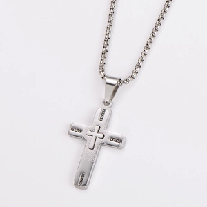Macro view of silver stainless steel cross pendant with intricate Greek key pattern
