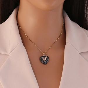 Close-up of heart-shaped natural stone pendant with gold diamond-set heart on a necklace