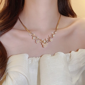 Close-up of golden floral necklace with frosted cherry blossom and pearls on a model