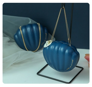 Detail of dark blue shell candy box with gold chain and pearl pendant accessory
