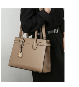 Close-up of khaki pebbled leather tote bag with gold studs and shoulder strap details