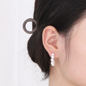 Close-up of elegant C-shaped gold earrings featuring vertical white pearls and zircon detail