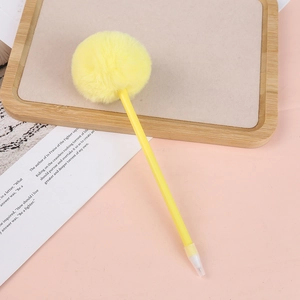 Detailed view of creative yellow pom pom ball pen on minimalist pink stationery background