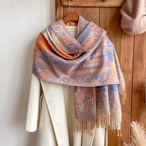 Detailed shot of ethnic paisley pattern scarf with fringes draped over a wool coat