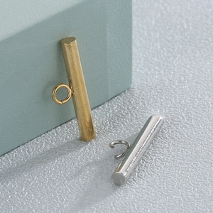 Detailed close-up of cylindrical gold and silver T-bar jewelry clasps with metal luster