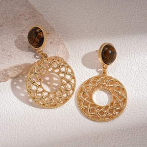 Detail of vintage round hollow mesh earrings with brown tiger eye stones on a stone base