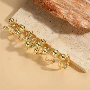 Ensemble de six bagues minimalistes dorées à perles présentées sur pierre et bois