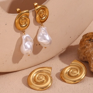 Detail of 18K gold plated conch spiral earrings with baroque pearls on stone texture