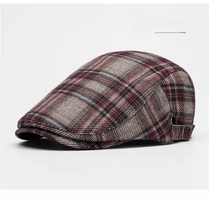 Detail view of the red plaid flat cap featuring a side metal buckle and woolen texture