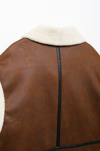 Detail view of brown suede jacket back with white faux fur collar and black leather trim