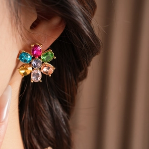 Close-up of vintage gold flower earring featuring colorful rhinestones on female model