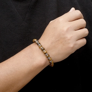 Brown tiger eye stone beaded bracelet with stainless steel spacers on a person's wrist