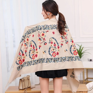 Close-up of colorful floral embroidery and fringe detail on a beige pashmina shawl